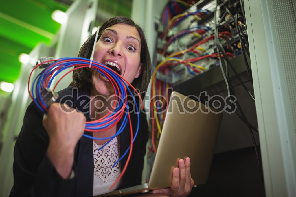 Frustrated technician eating wire and holding laptop